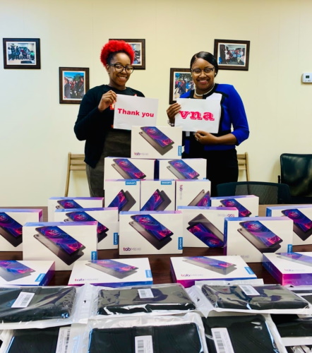 Staff holding VNA and thank you signs with donated tablest on a table